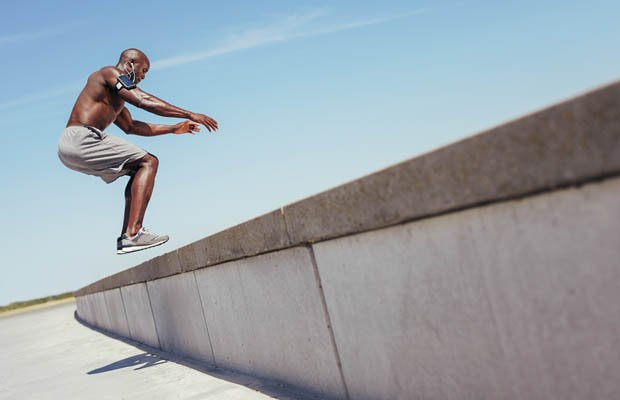 Muscular man doing box jumps outdoors.